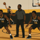 Youth basketball players doing layups and defensive slides during a pre-game warm-up with coach giving instructions