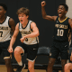 Youth basketball players celebrating enthusiastically from the bench during a game.
