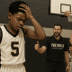 Youth basketball player reacts to a missed shot while teammates and coach encourage him to keep going.