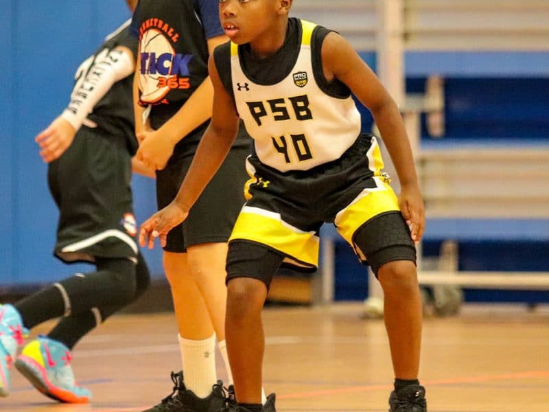 Young boy playing defense in a youth basketball game