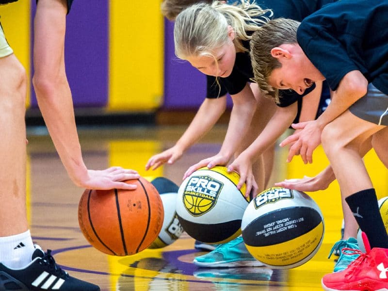 Children practice dribbling drills at a Pro Skills Basketball camp