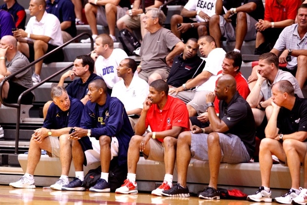 College Basketball Coaches sit in the bleachers in a gymnasium