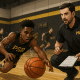 Youth basketball player diving for a loose ball at tryouts while coaches observe.