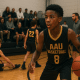 Youth basketball player warming up before an AAU game while parents and coaches observe.