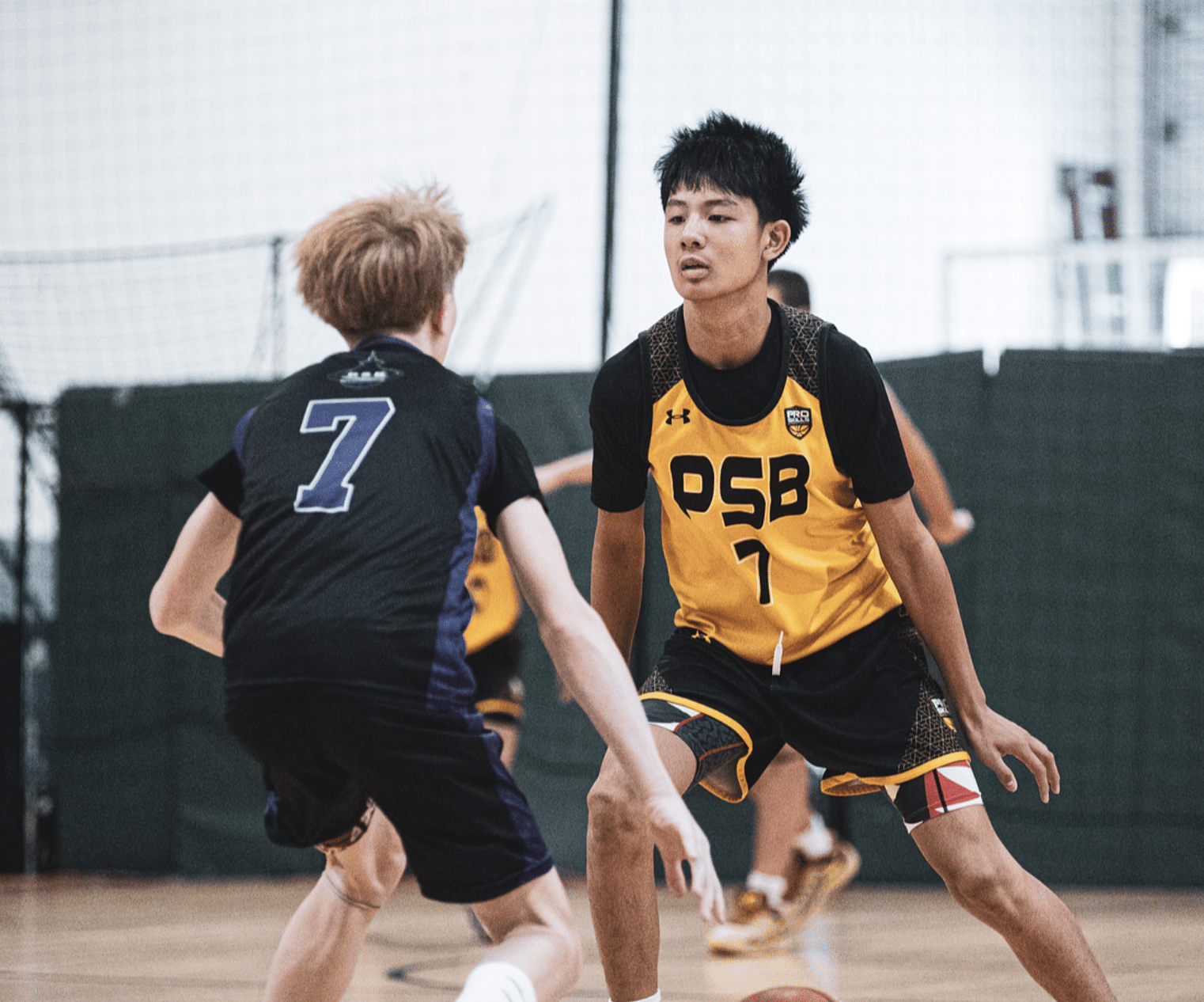 Youth basketball player guarding an opponent, PSB player in yellow jersey on defense at tournament