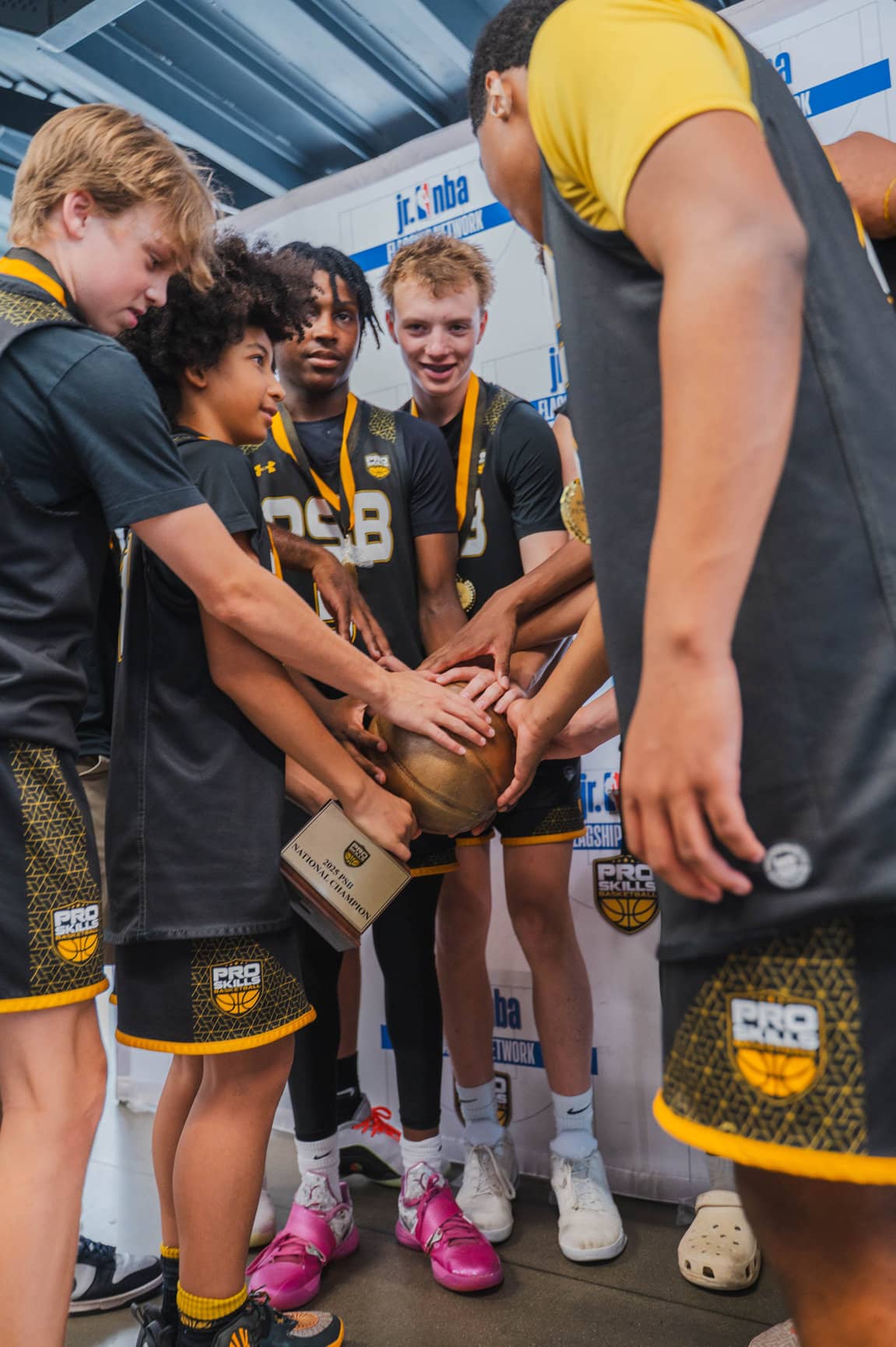 PSB youth basketball players putting hands together in team unity before an AAU game
