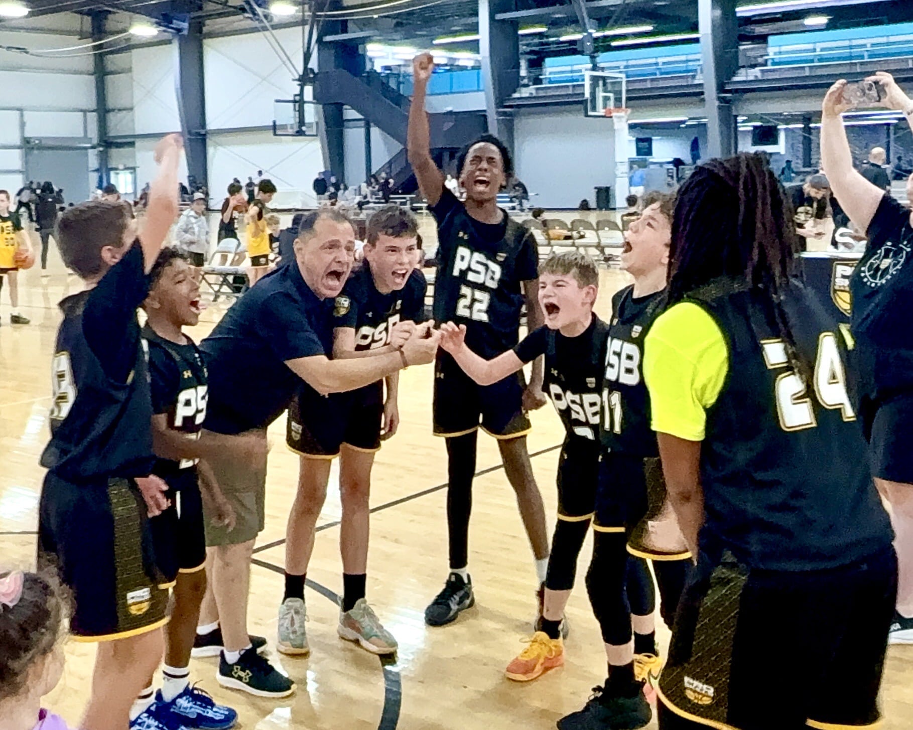 PSB coach celebrating with youth basketball team after a win