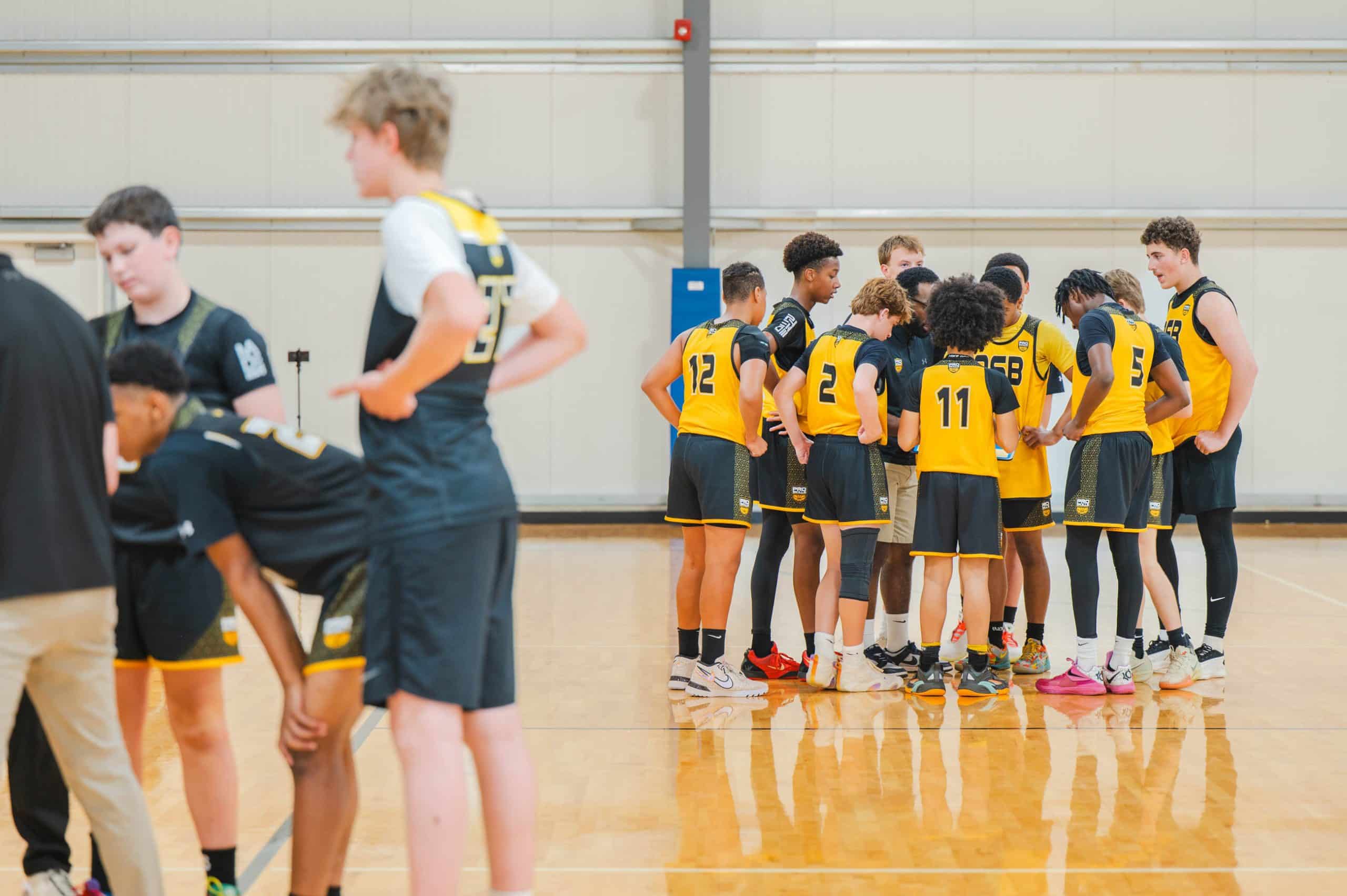 PSB boys team huddle on the court in yellow jerseys