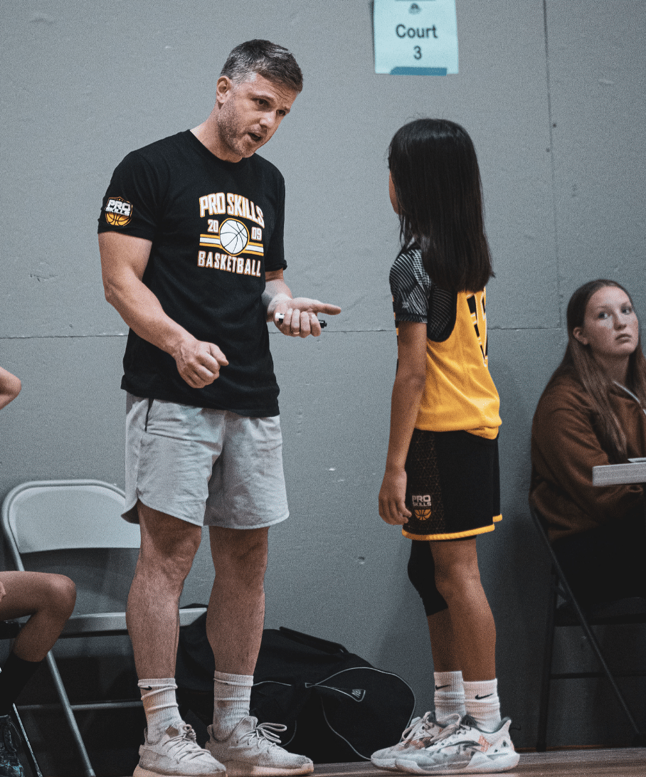 Youth basketball coach giving sideline instruction to a player during a game