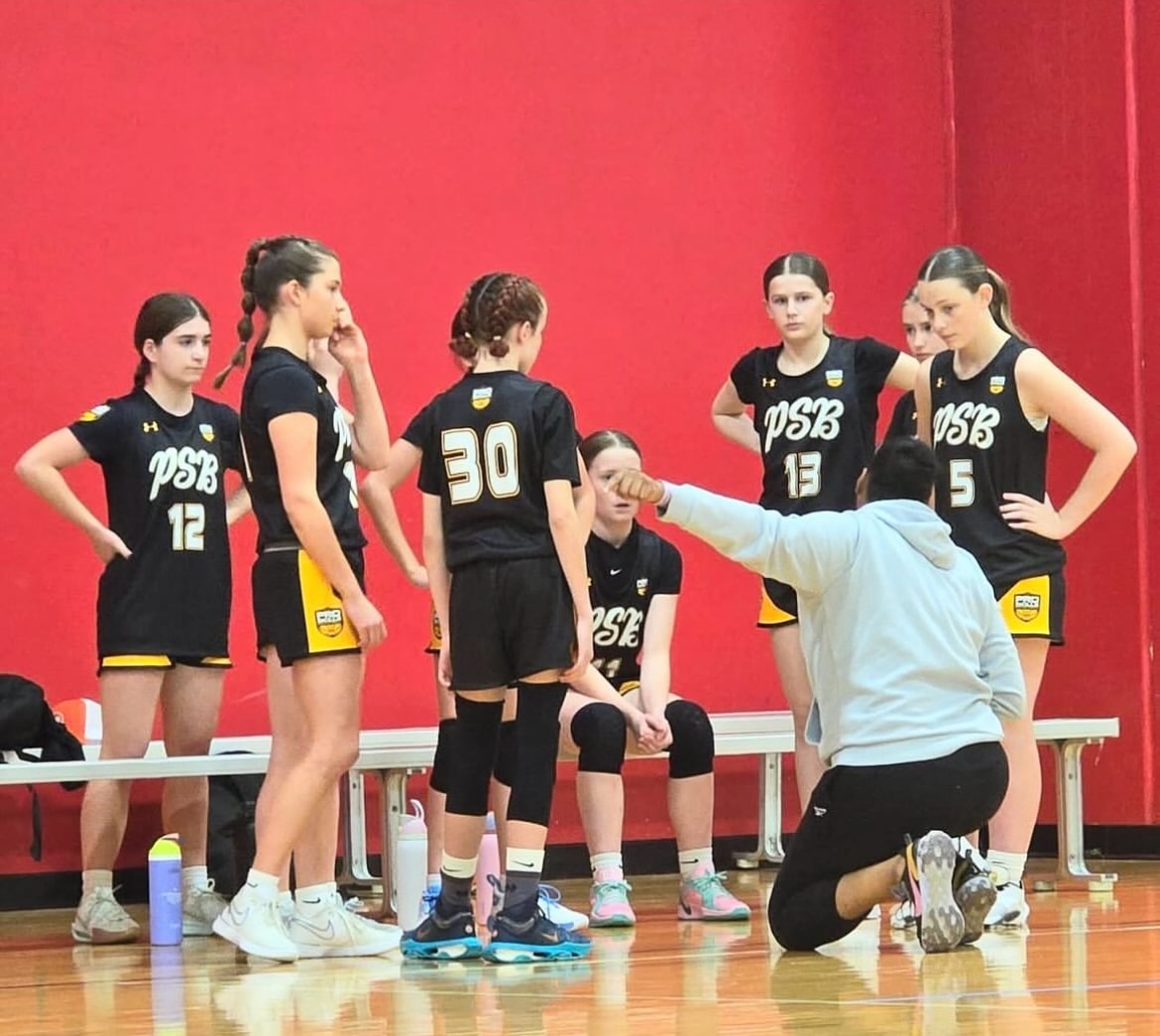 PSB girls basketball team in huddle with coach during AAU timeout
