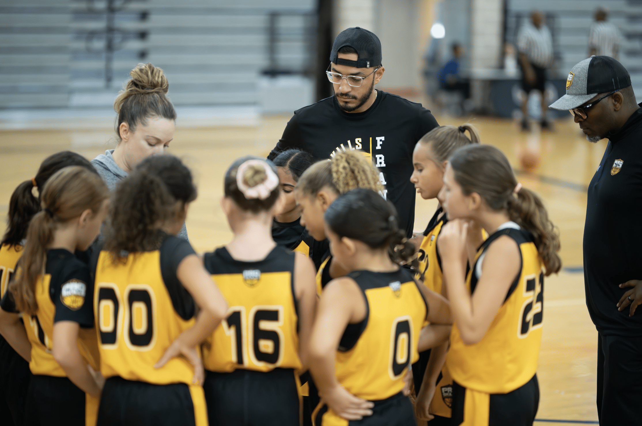PSB girls basketball coach leading young players in huddle during AAU tournament