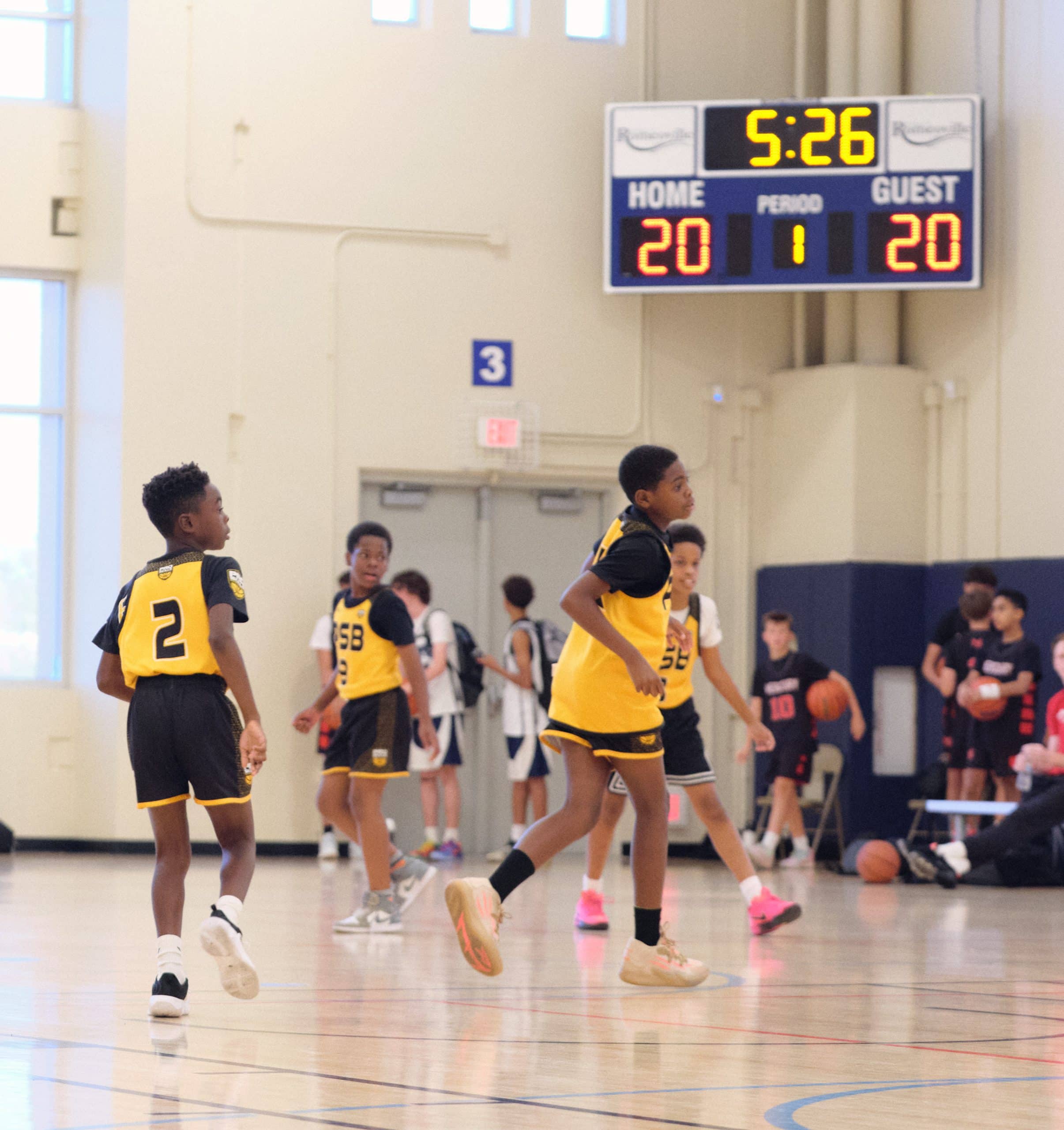 Youth basketball game with the scoreboard in the background