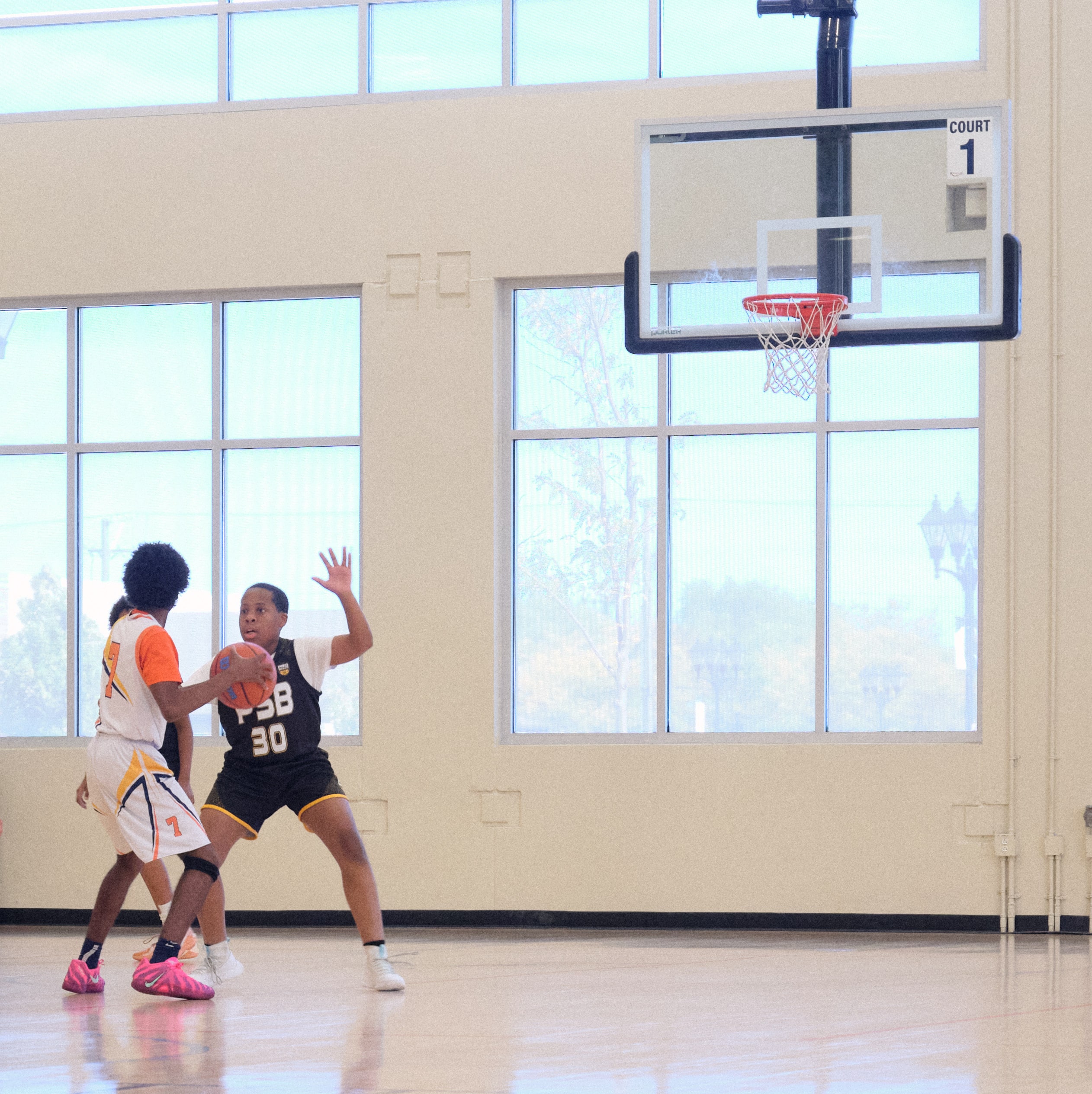 Middle school club basketball players in a tournament game seen from the baseline
