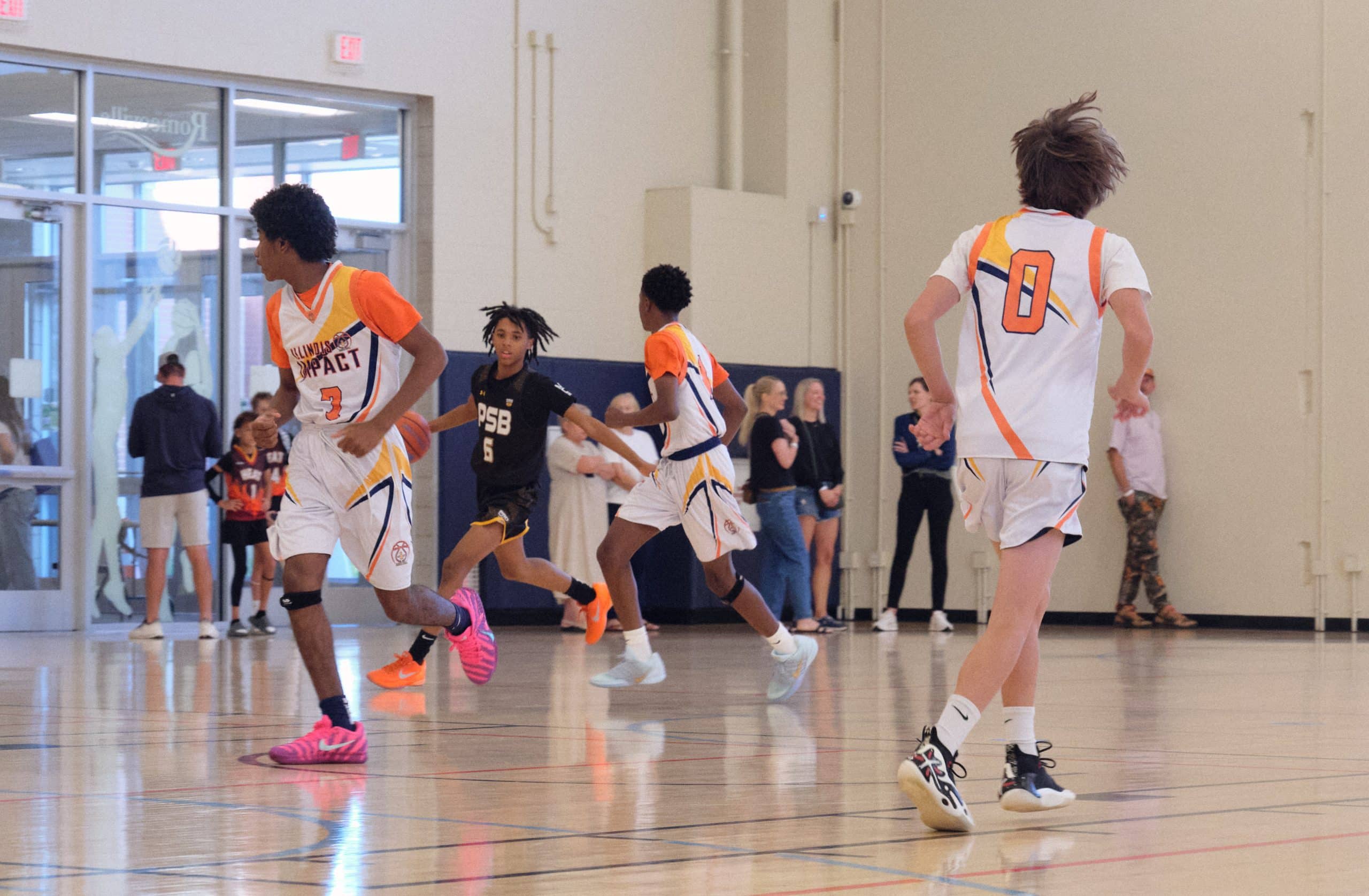 Middle school club basketball players running a fast break in a tournament game
