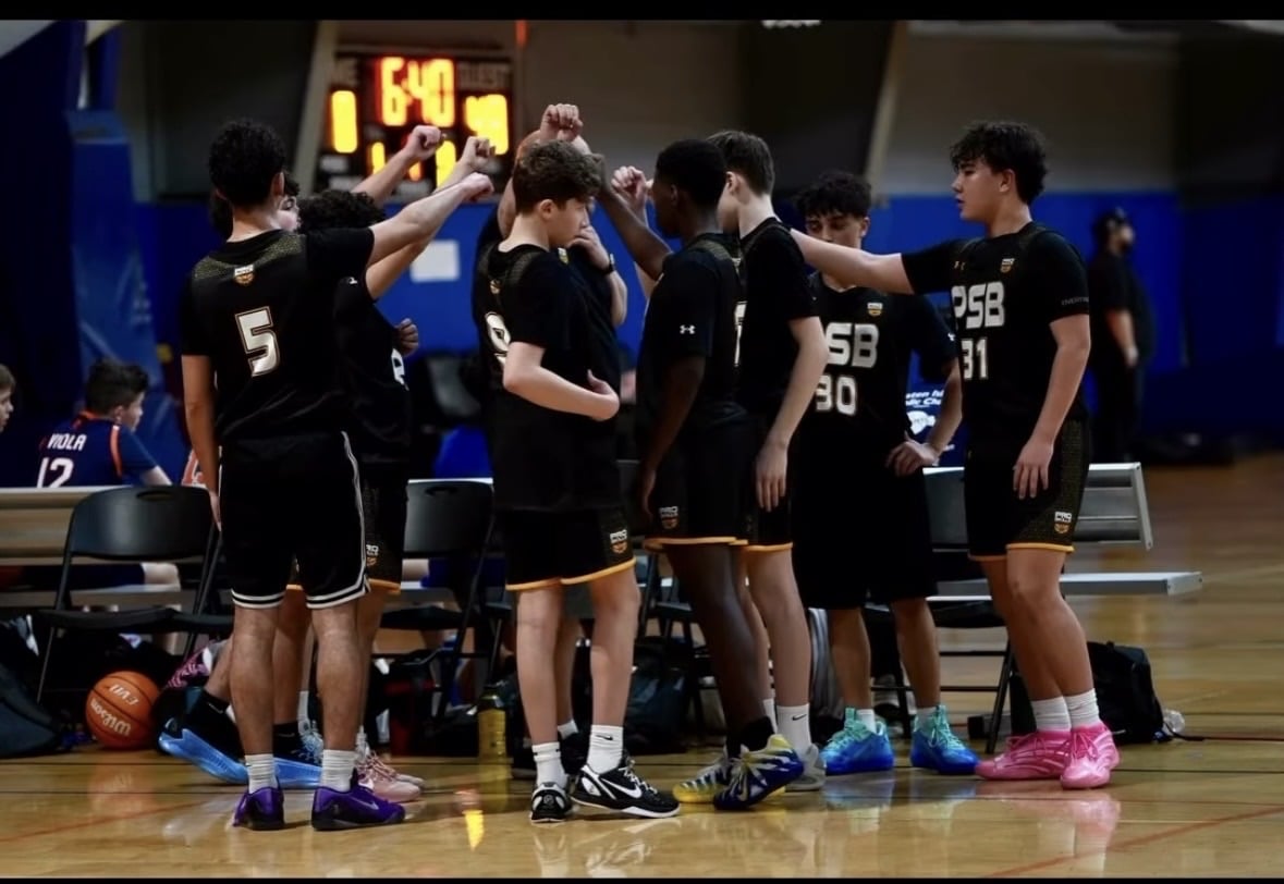 Youth basketball team huddling on the court with their coach