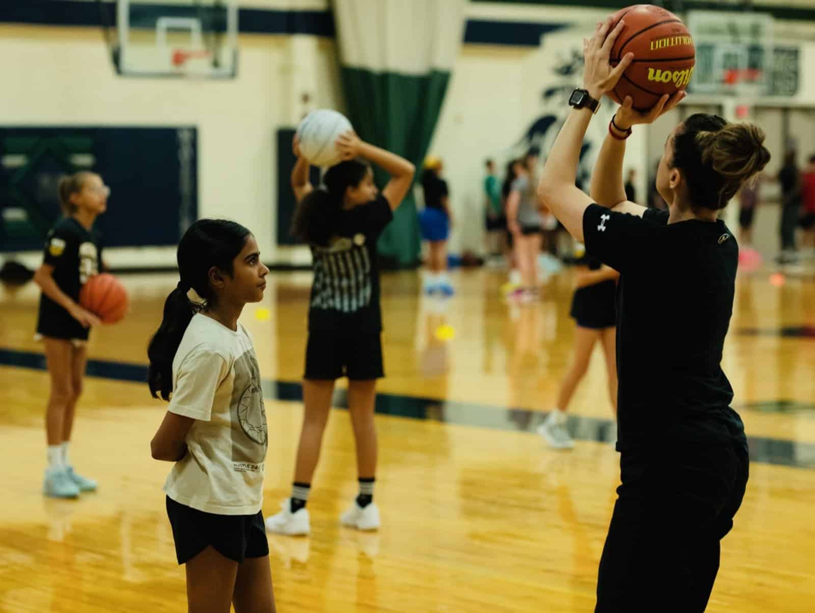 A coach showing youth basketball players how to shoot at a skills clinic